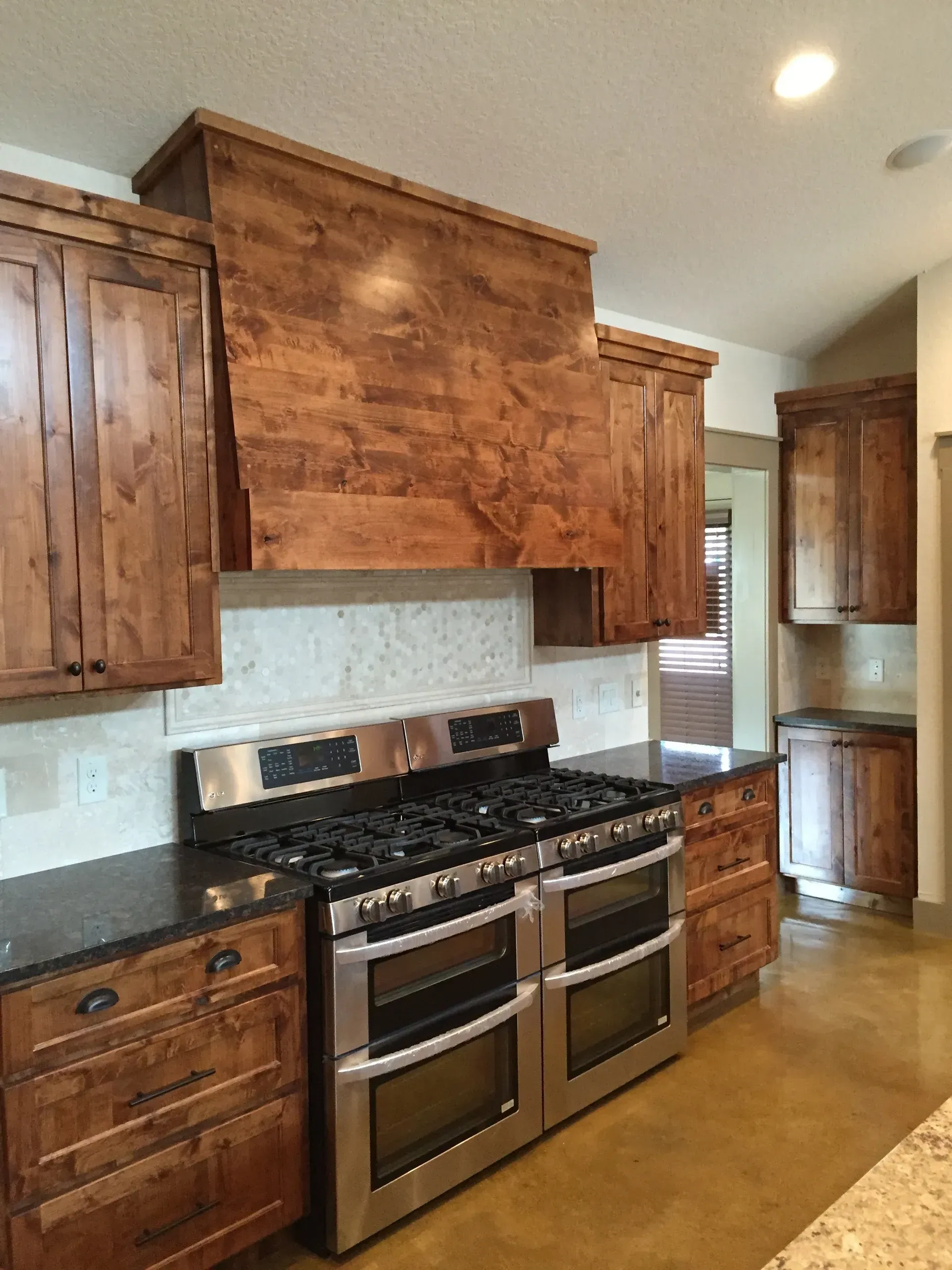 Kitchen with wooden cabinets, stainless steel stove, and dark countertops.