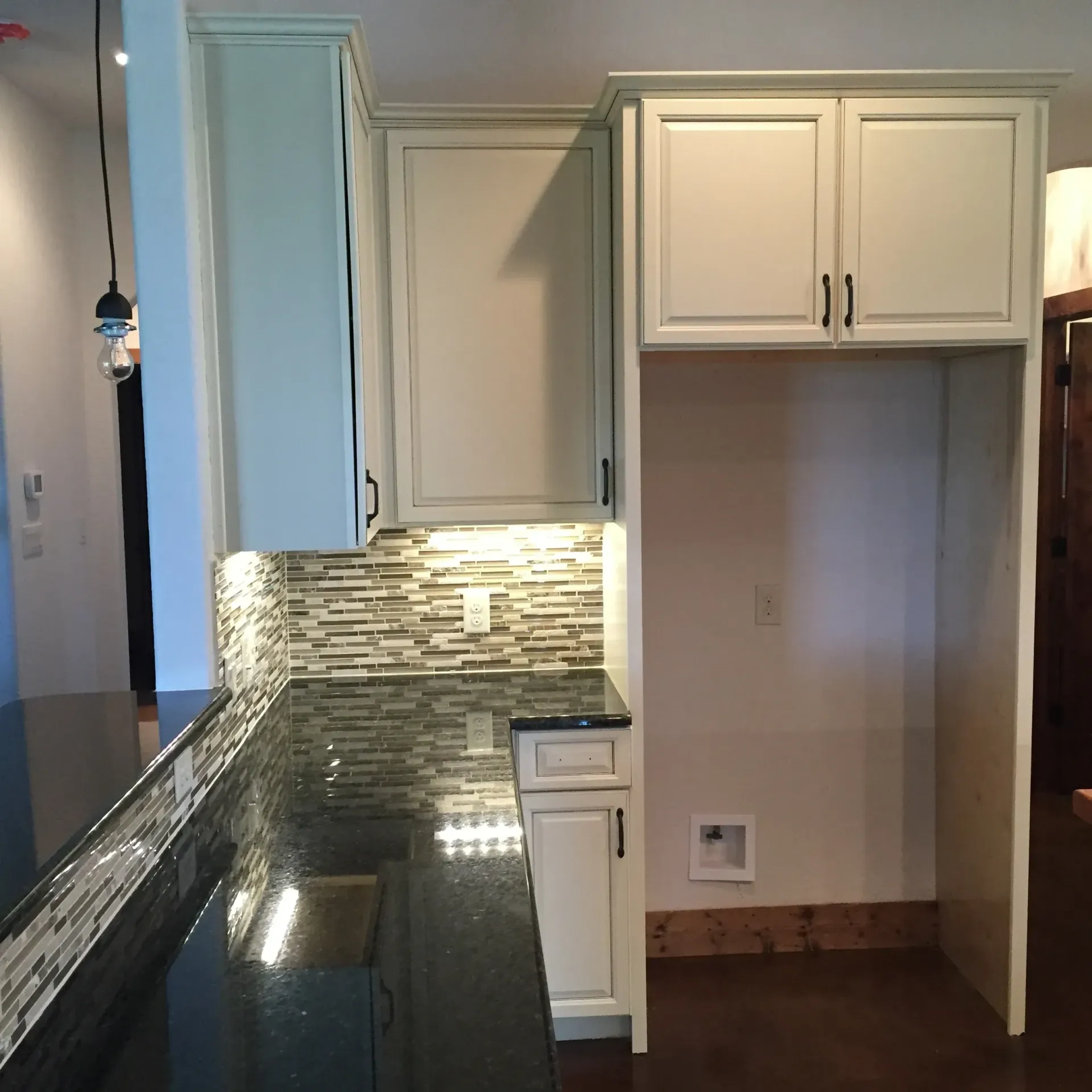 Kitchen with white cabinets, dark countertops, and a tiled backsplash.