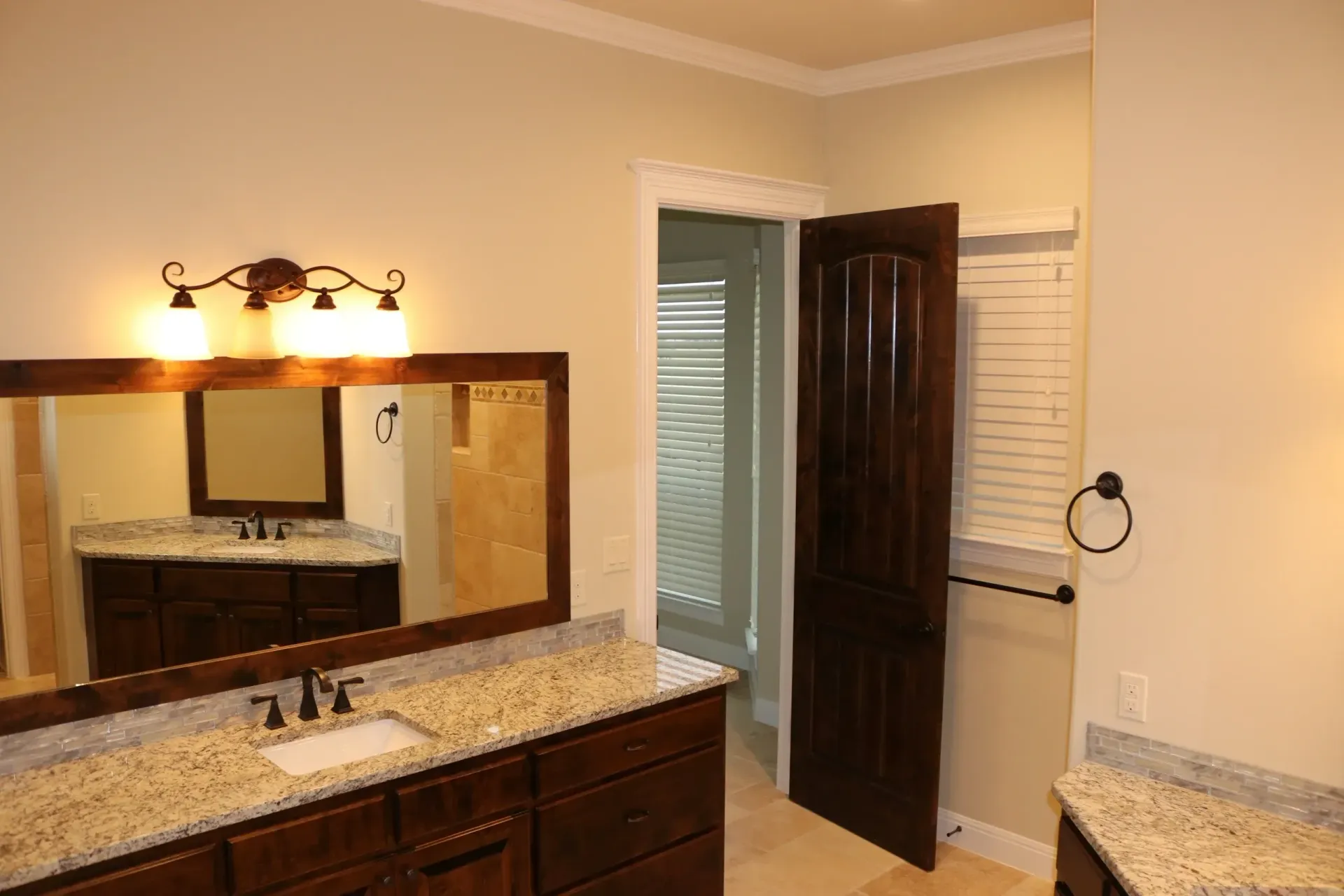 Bathroom with a dark wooden vanity and countertop, mirror, and open door to a shower.