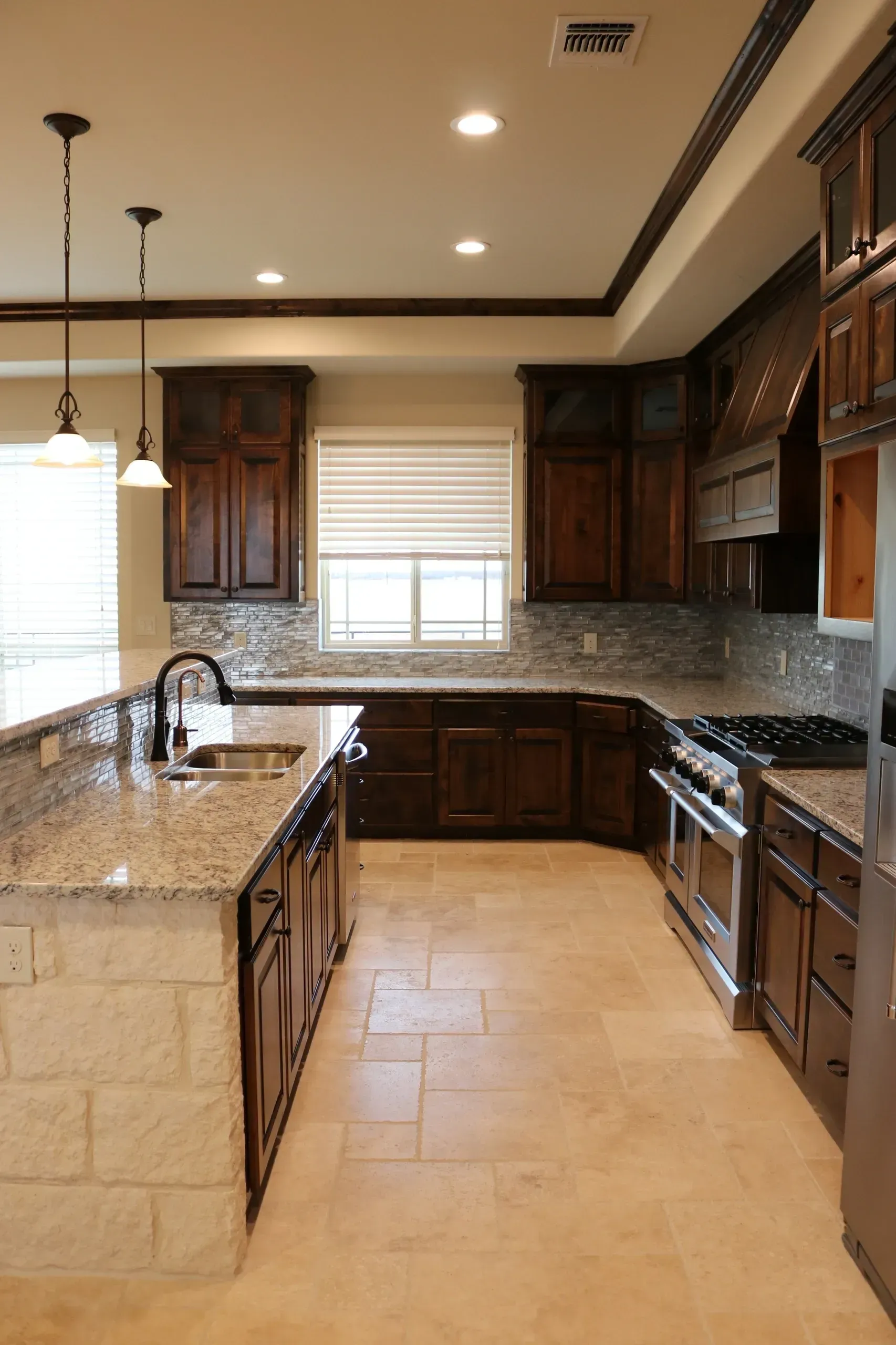 Kitchen with dark wood cabinets, granite countertops, and stone island.