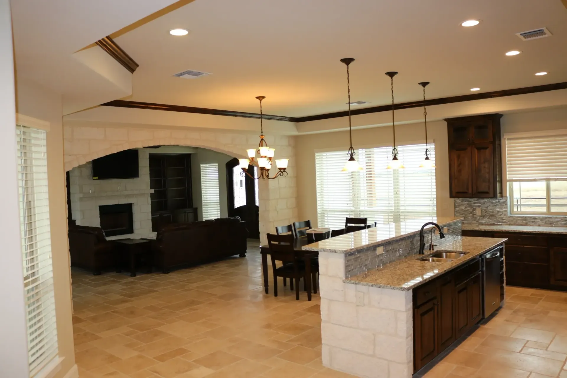Open-concept kitchen and living room with brown cabinets, island, and dining table.