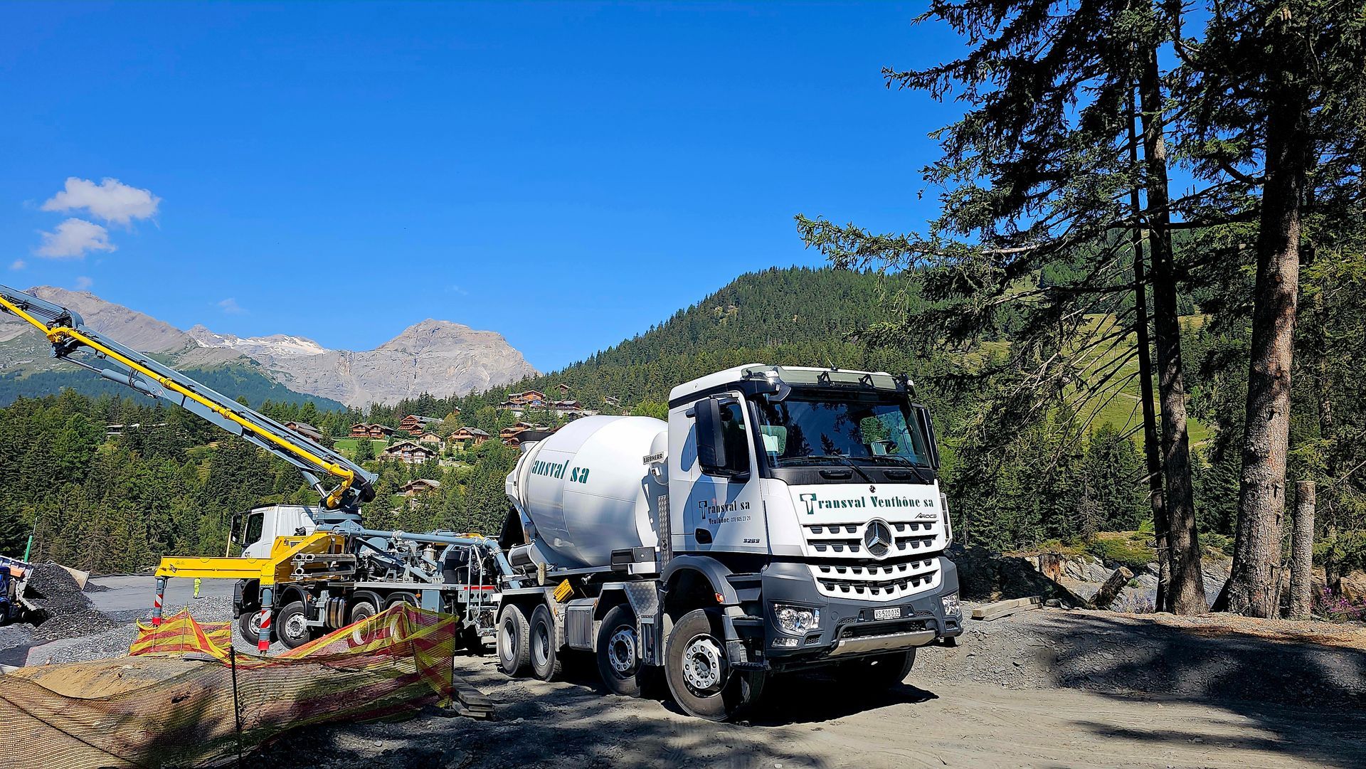 Un camion à béton roule sur un chemin de terre dans les montagnes.