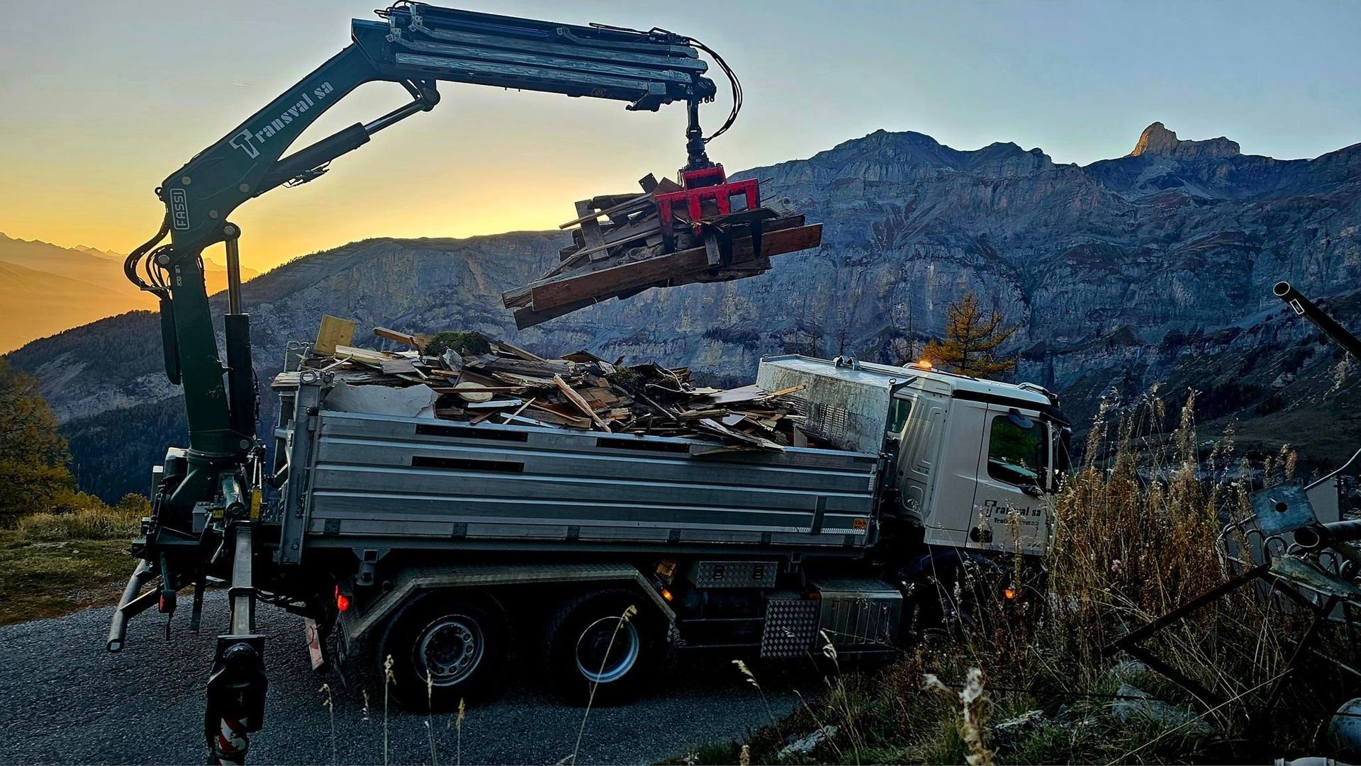 Une grue soulève un tas de bois d'un camion.
