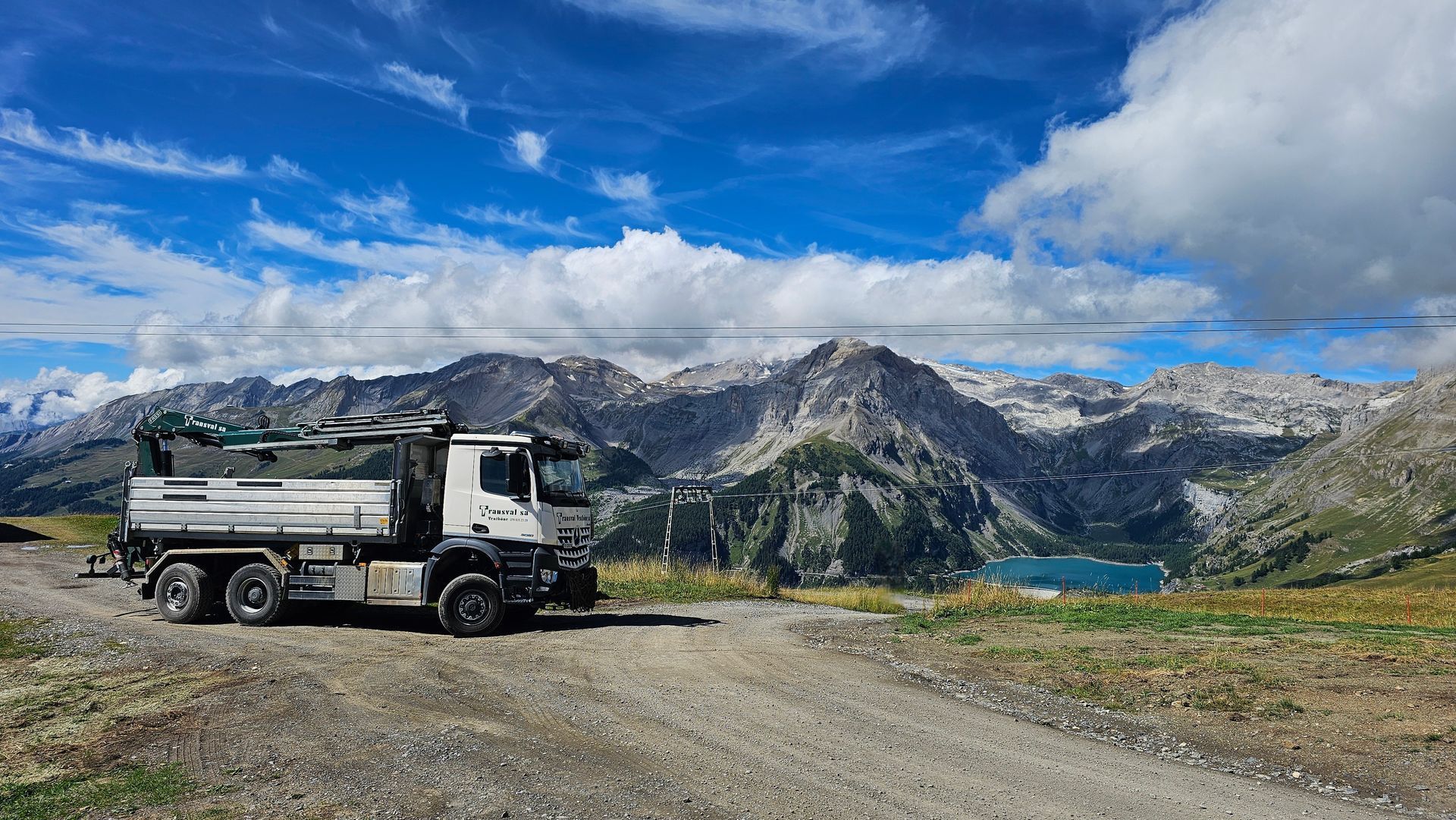 Un camion à benne basculante est garé sur le bord d'un chemin de terre dans les montagnes.