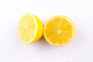 Two lemon halves on a white surface; bright yellow flesh, white pith, and yellow skin.