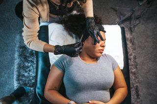 Woman having ear treatment; person in gloves adjusting her hair.