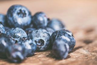 Blueberries, close-up, scattered on a rustic wooden surface.