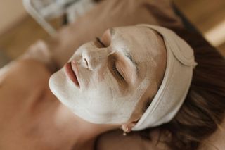 Person with a face mask on, lying down with a headband.