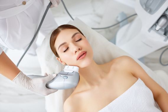 Woman receiving facial skin tightening treatment with a handheld device.