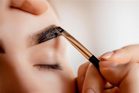 Person's eyebrow being professionally shaped with a brush, close-up.