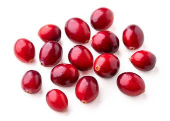 Scattered ripe, red cranberries against a white background.