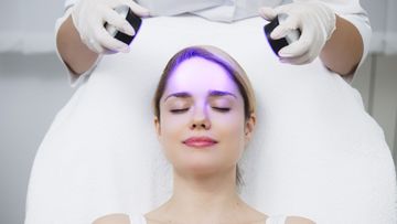 Woman receiving blue light therapy on her face at a spa.