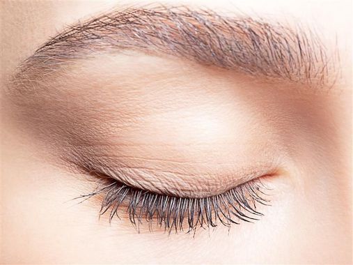 Closed eye with long eyelashes and a full eyebrow.