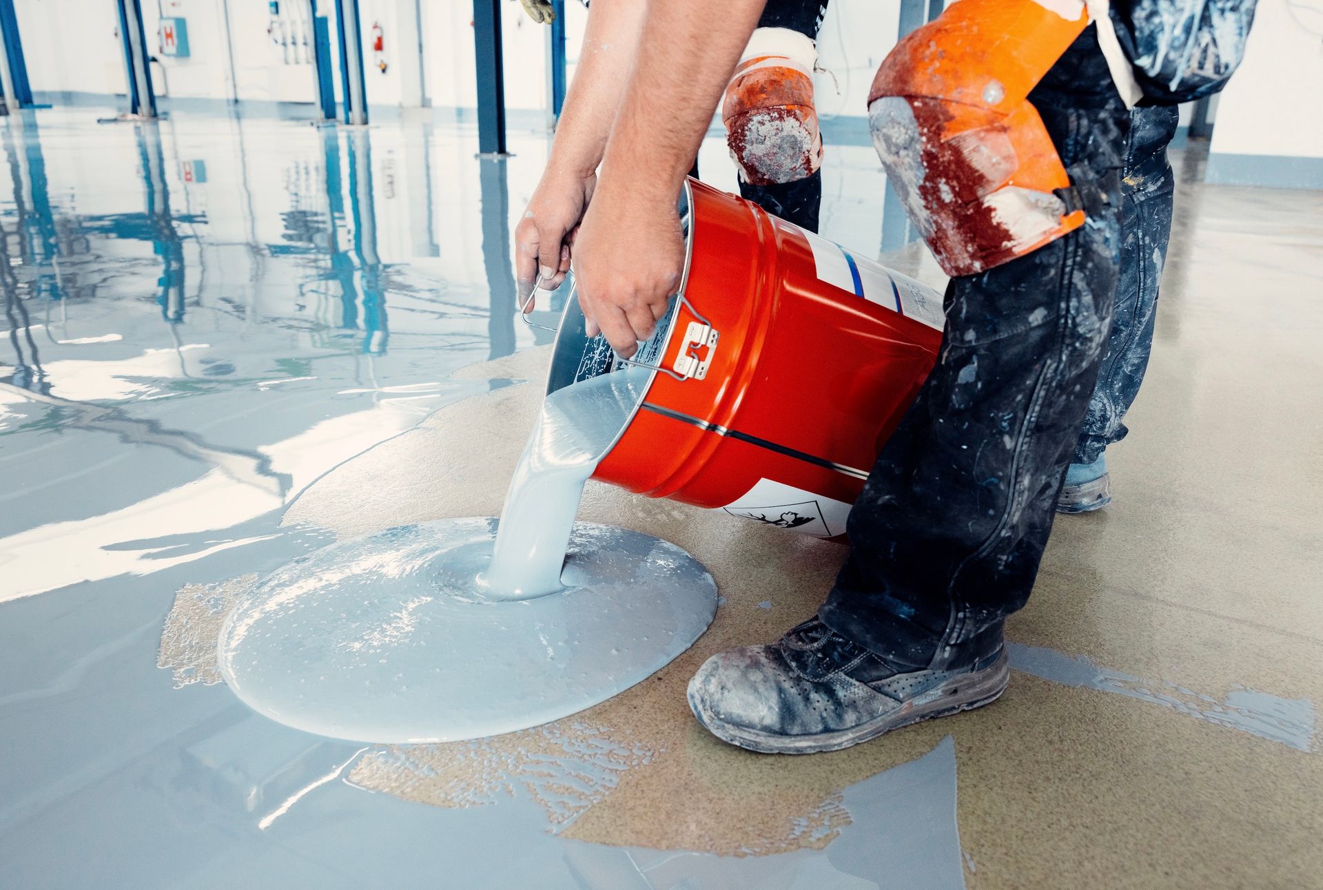A man is pouring epoxy into a hole in the floor.