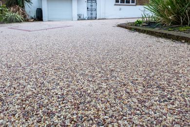 A gravel driveway with a garage in the background.