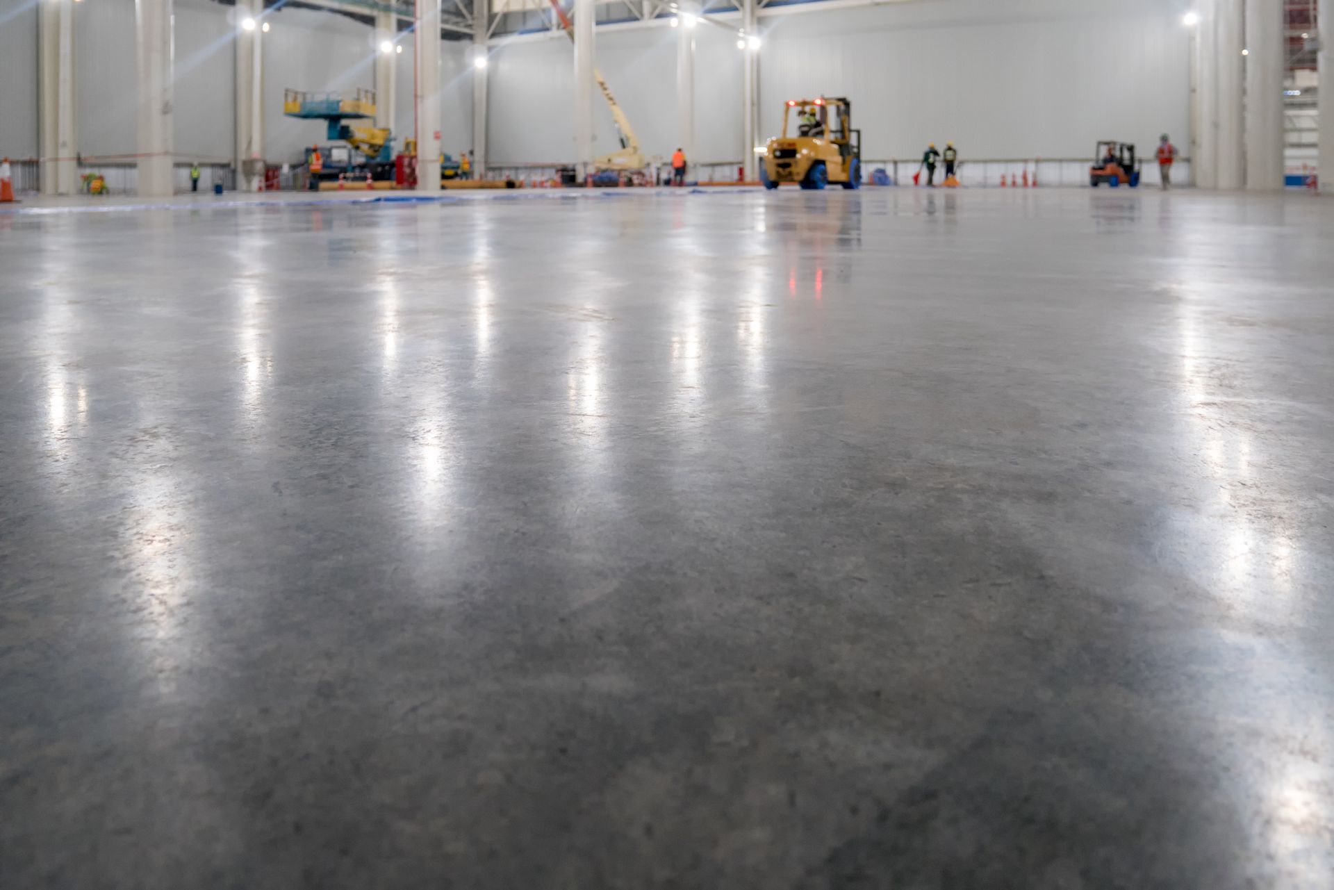 A large warehouse with a shiny concrete floor and a forklift in the background.