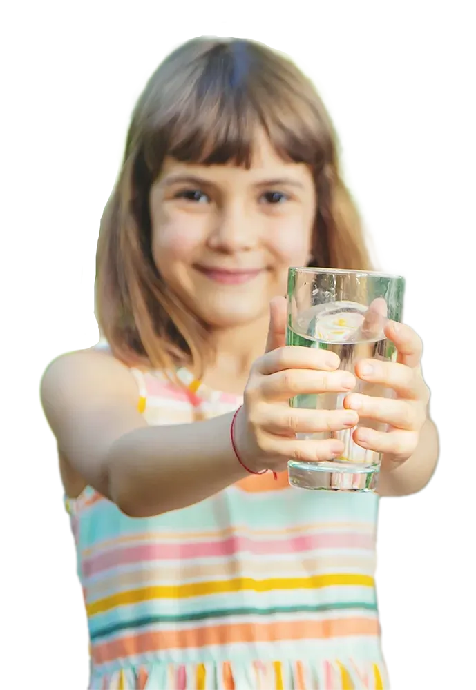 A little girl is holding a glass of water in her hands.