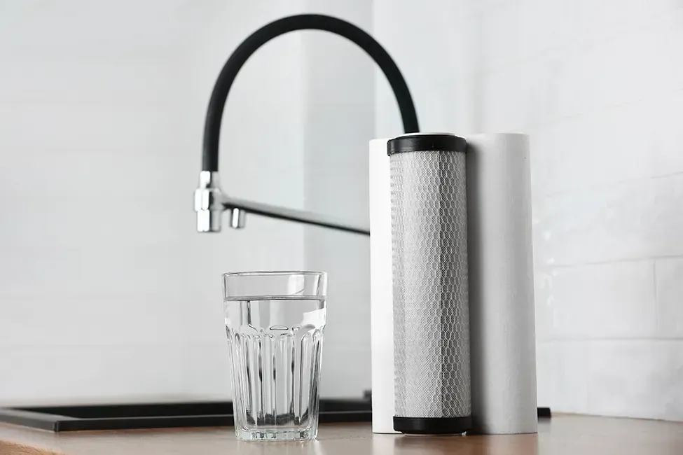 A glass of water is sitting on a counter next to a faucet.