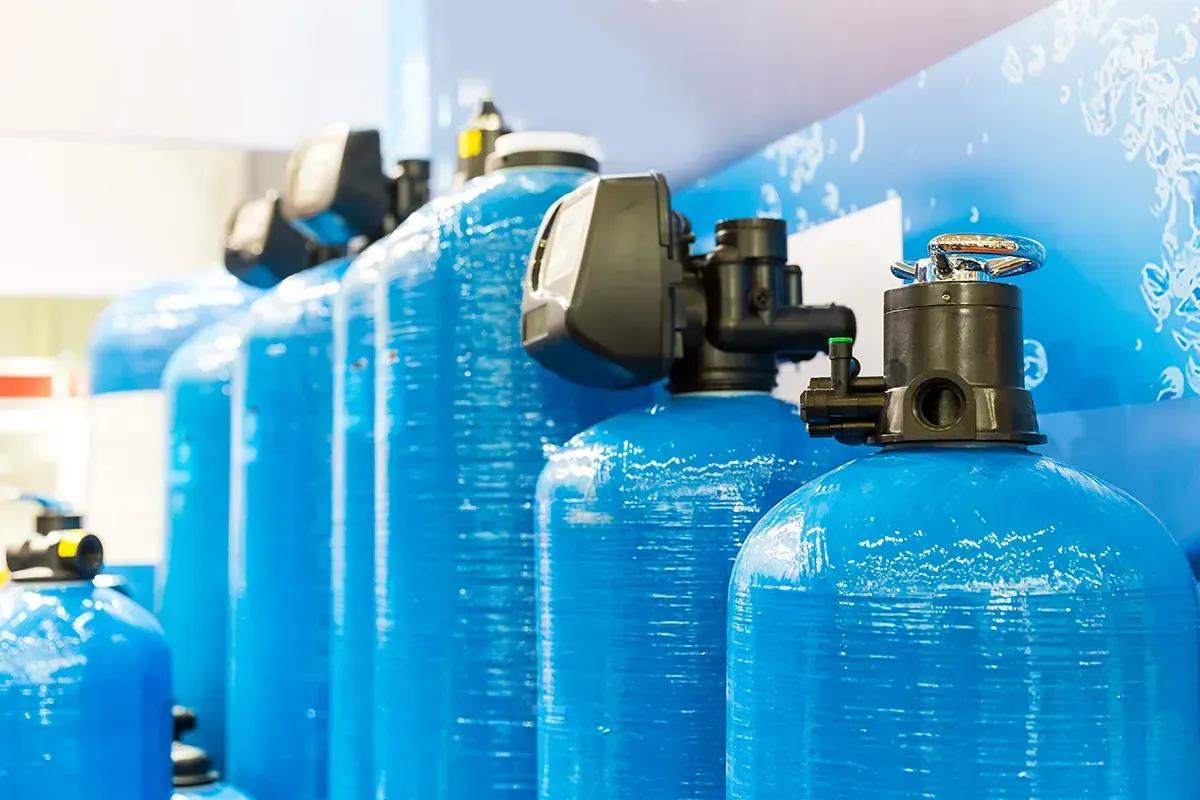 A row of blue water filters are lined up on a wall.