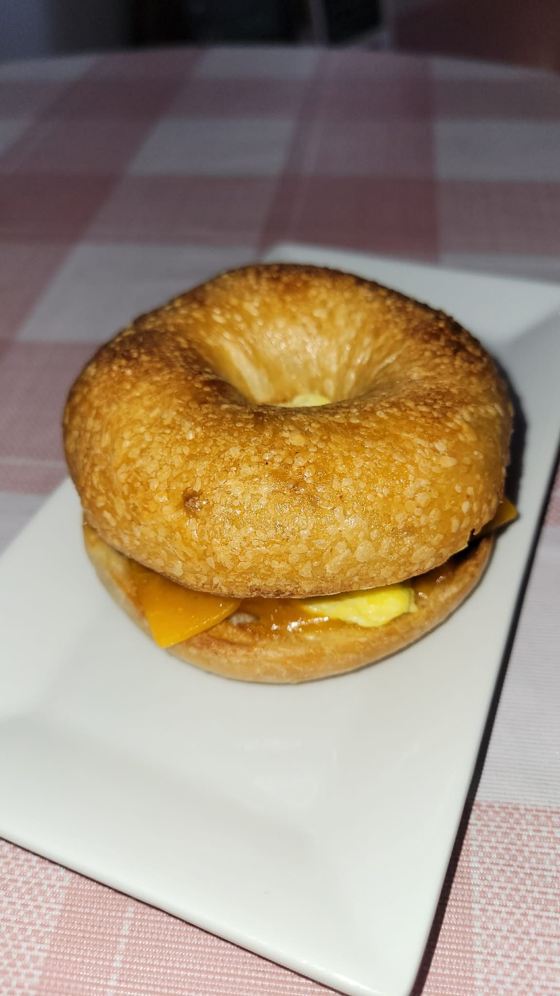 Bagel sandwich with melted cheese on a white plate