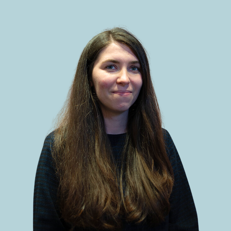 A woman with long brown hair is wearing a black sweater