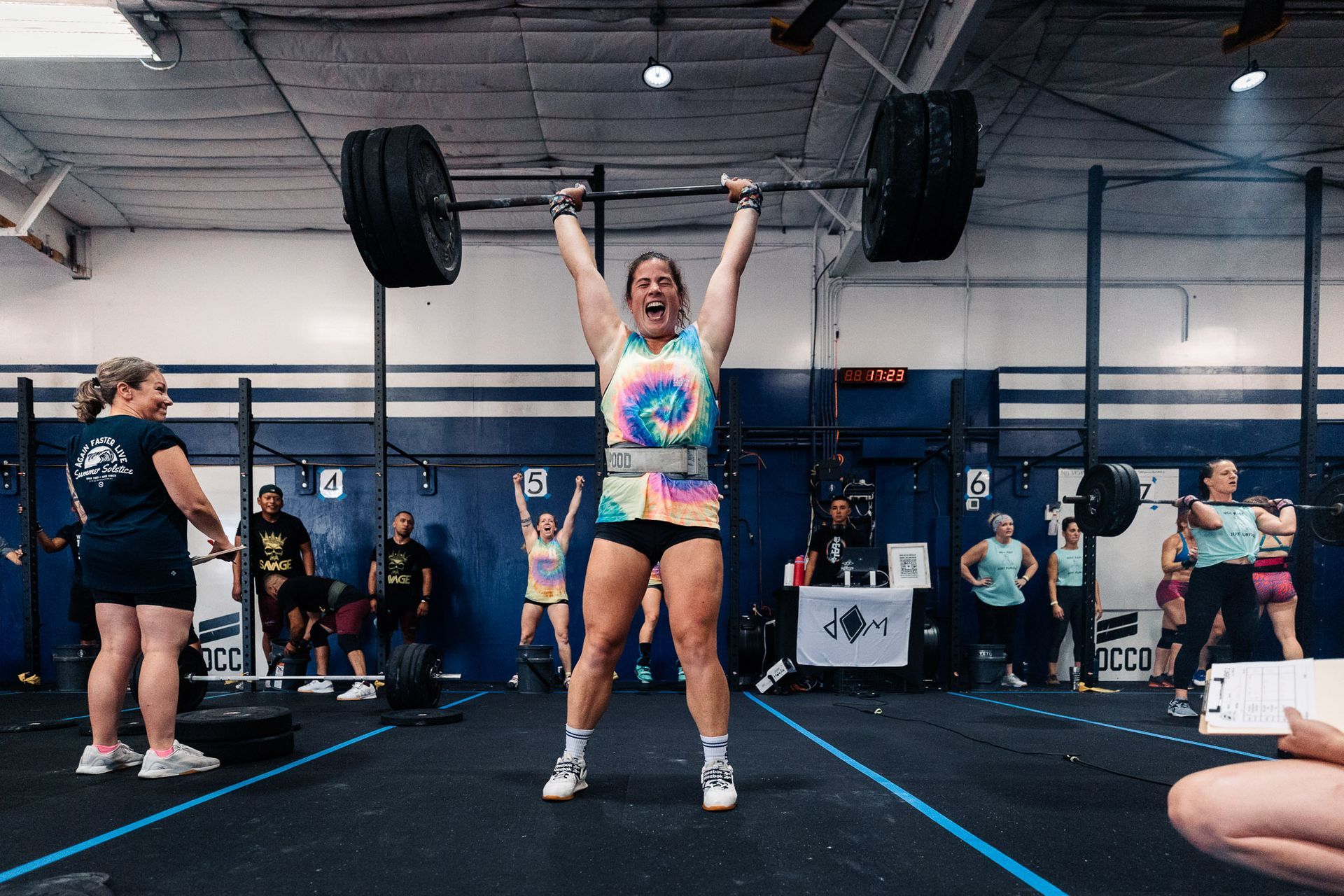 A woman is lifting a barbell in a gym.