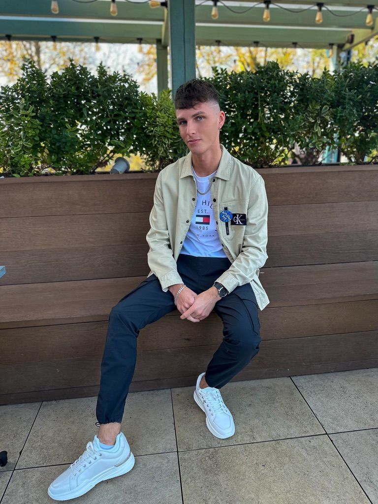 A young man is sitting on a wooden bench.