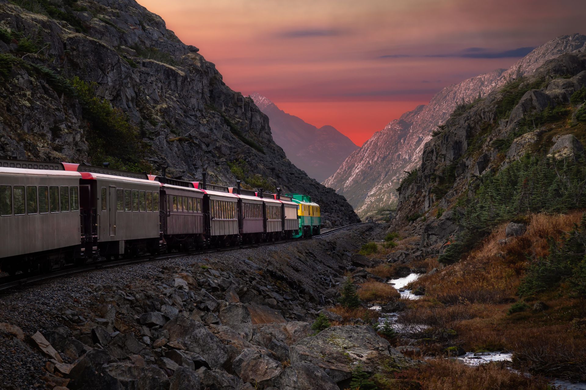 train with many wagons moving through the mountains of alaska in the USA