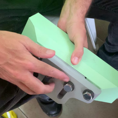 Person holding a light green sharpening stone attached to a metal base with bolts.