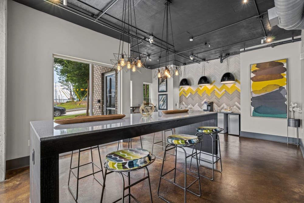Apartment kitchen with a long bar table, designer lighting, and stools at Skyline West in Atlanta, GA.