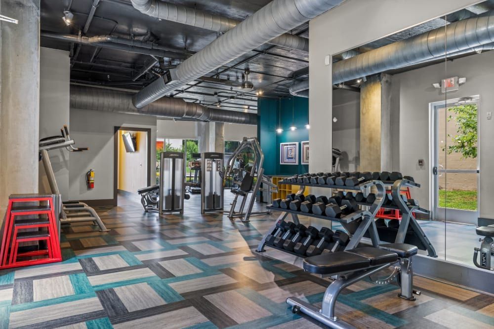 High ceiling fitness center with a lot of equipment and a large mirror at Skyline West in Atlanta, GA.