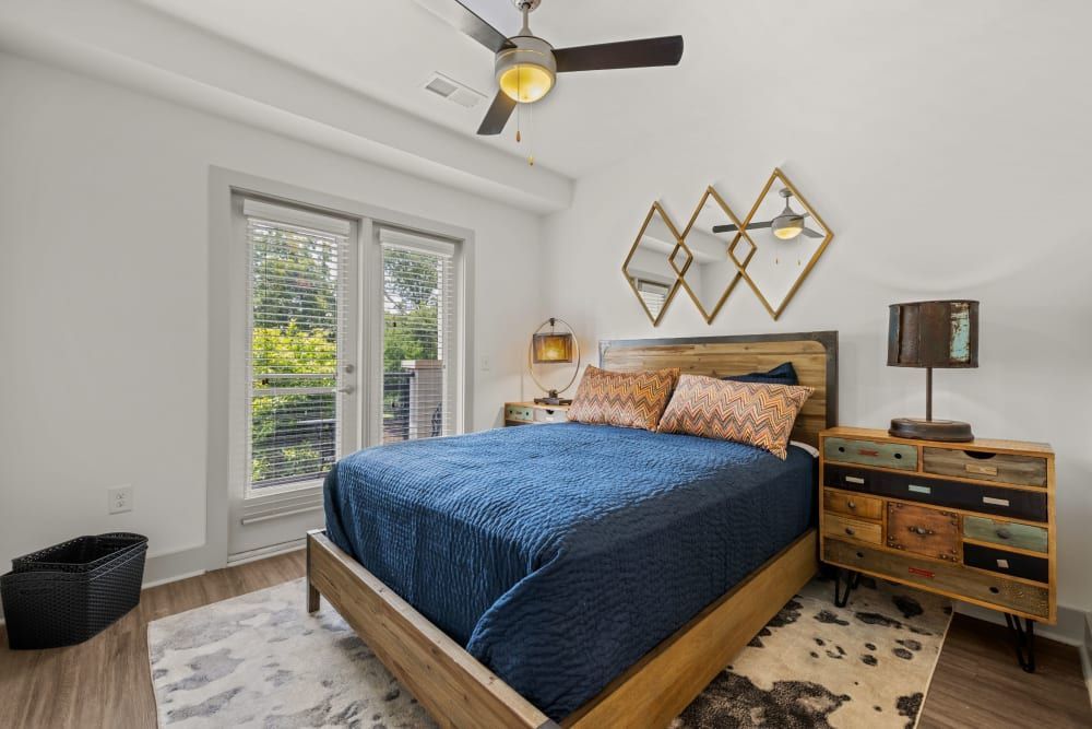 Spacious bedroom with a bed, dresser, nightstand, and ceiling fan at Skyline West in Atlanta, GA.