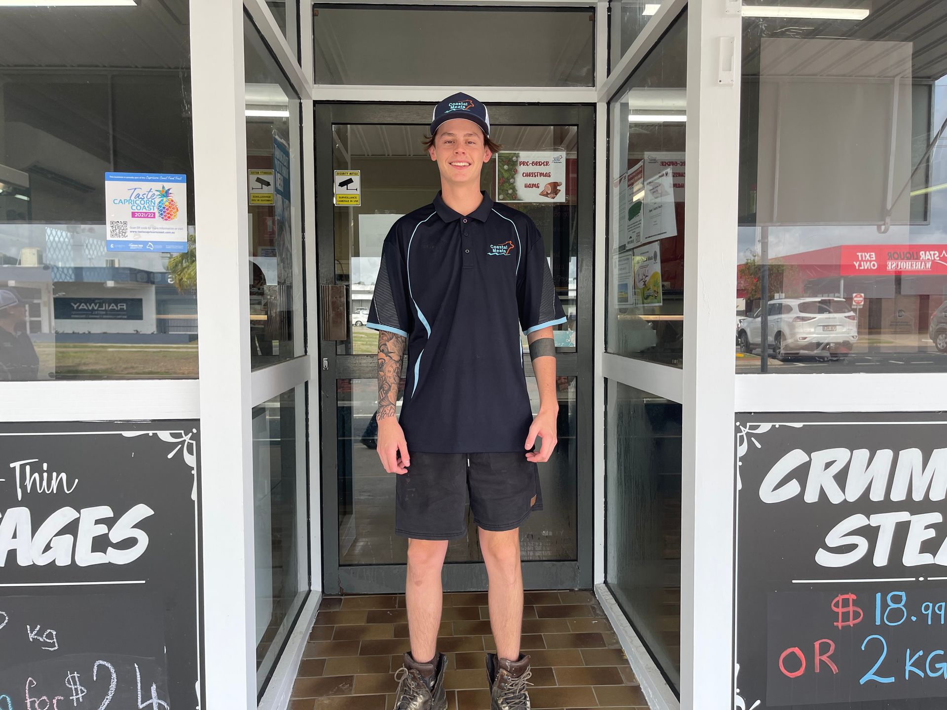 A Young Man Wearing a Uniform Stands in the Doorway of a Shop — Coastal Meats in Yeppoon, QLD