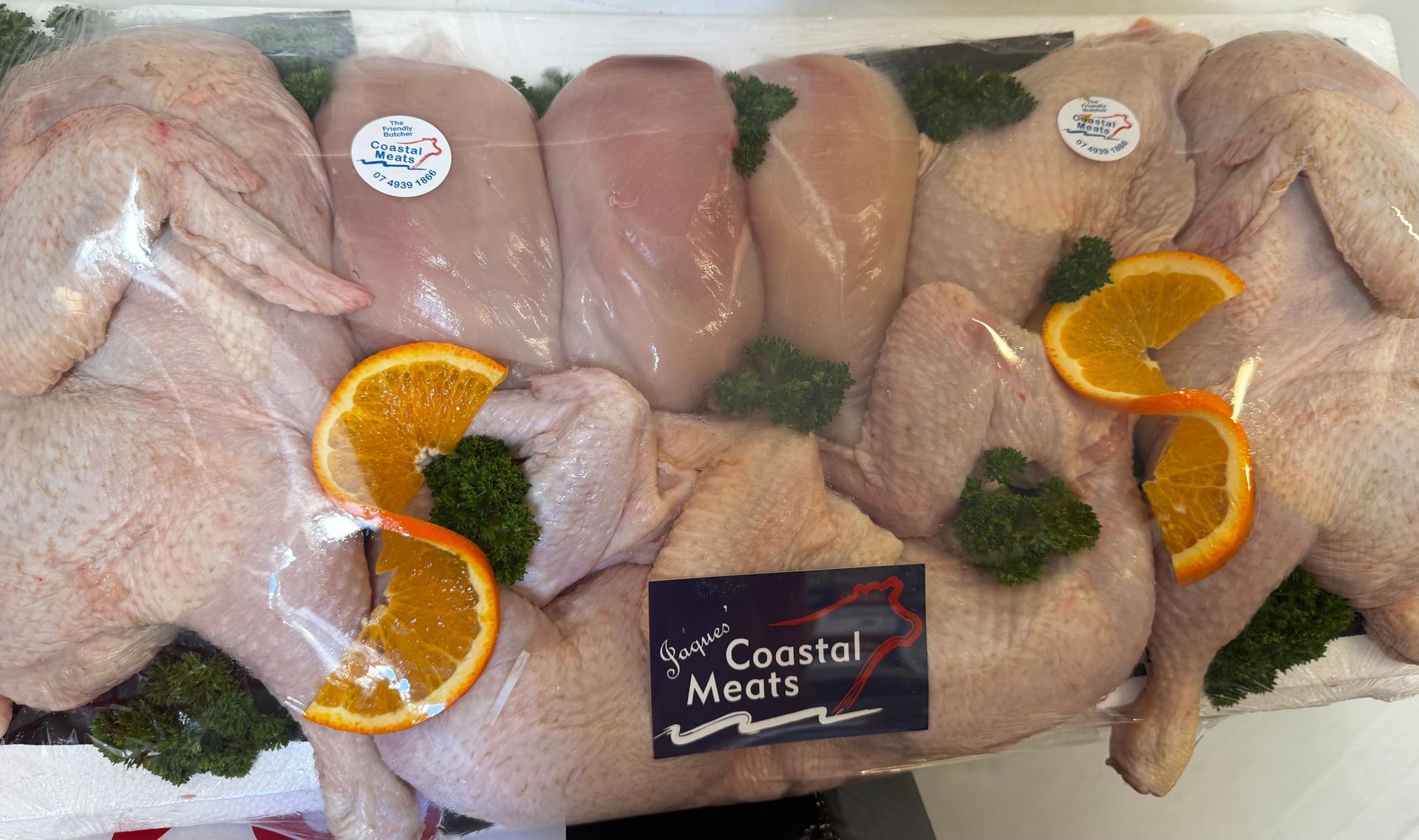 Prepackaged raw poultry cuts with orange slices and Coastal Meats branding — Coastal Meats in Yeppoon, QLD