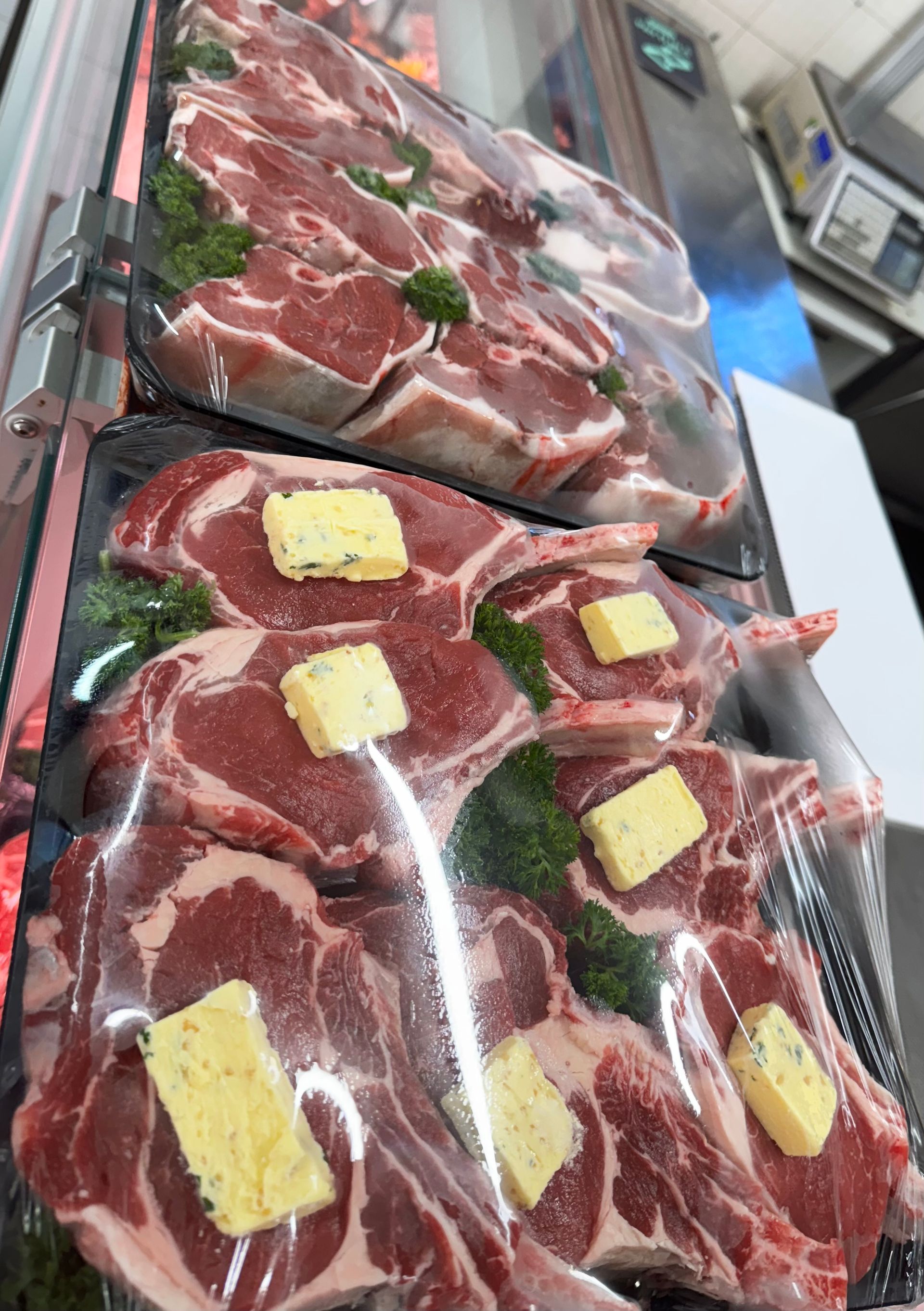 Packaged raw steaks with butter pats, displayed in a butcher shop, wrapped in plastic — Coastal Meats in Yeppoon, QLD
