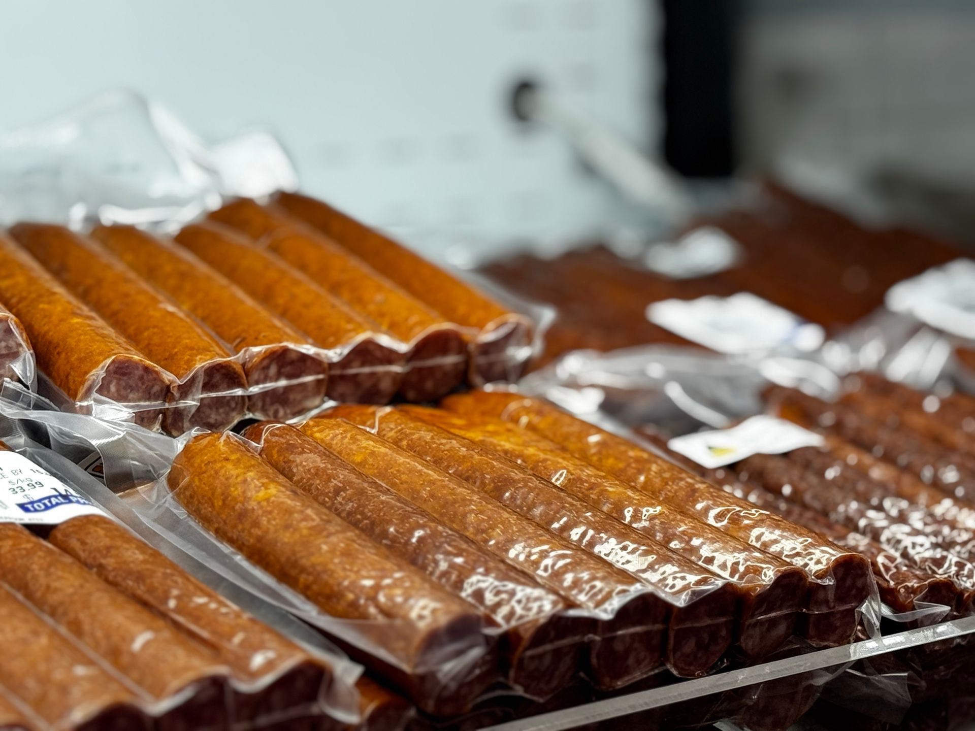 Packaged sausages on display, brown, in transparent plastic, on shelves — Coastal Meats in Yeppoon, QLD