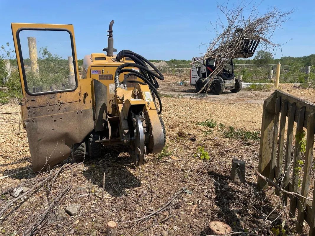 A yellow tractor is sitting in the middle of a dirt field.