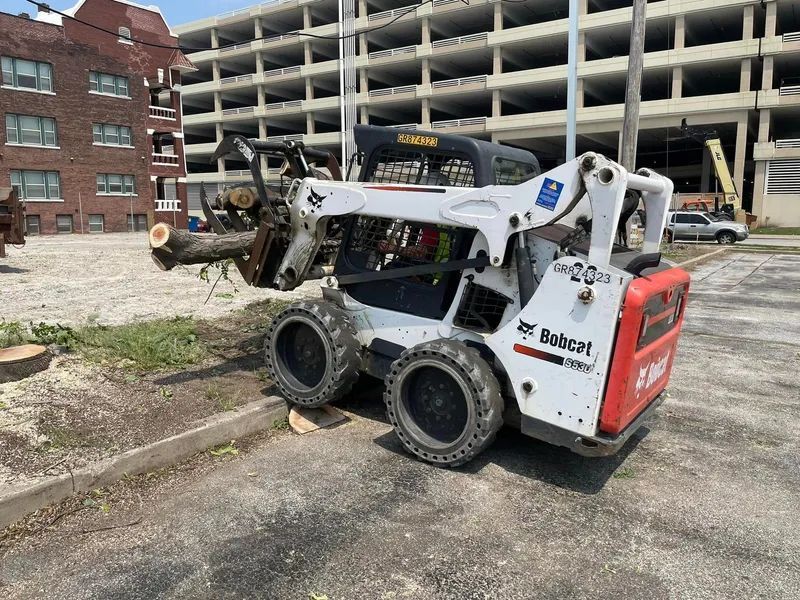A bobcat skid steer is parked in a parking lot in front of a building.