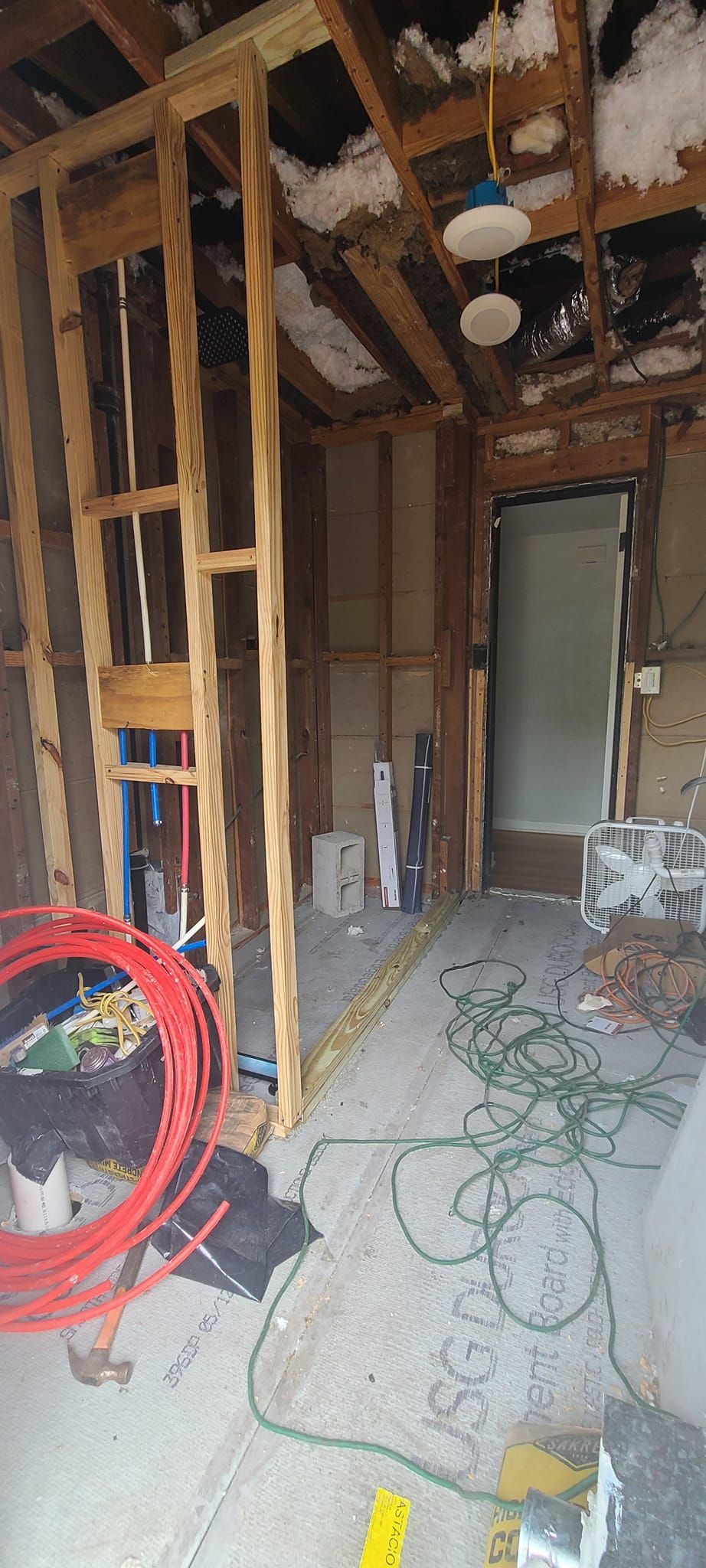 A room under construction with a ladder and a hose.