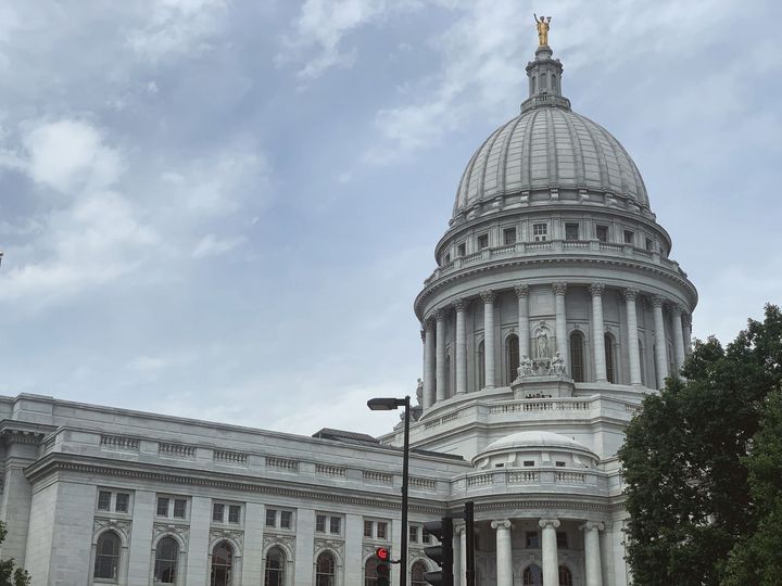 Man in suit, sitting at desk, reviewing papers, with pen in hand.