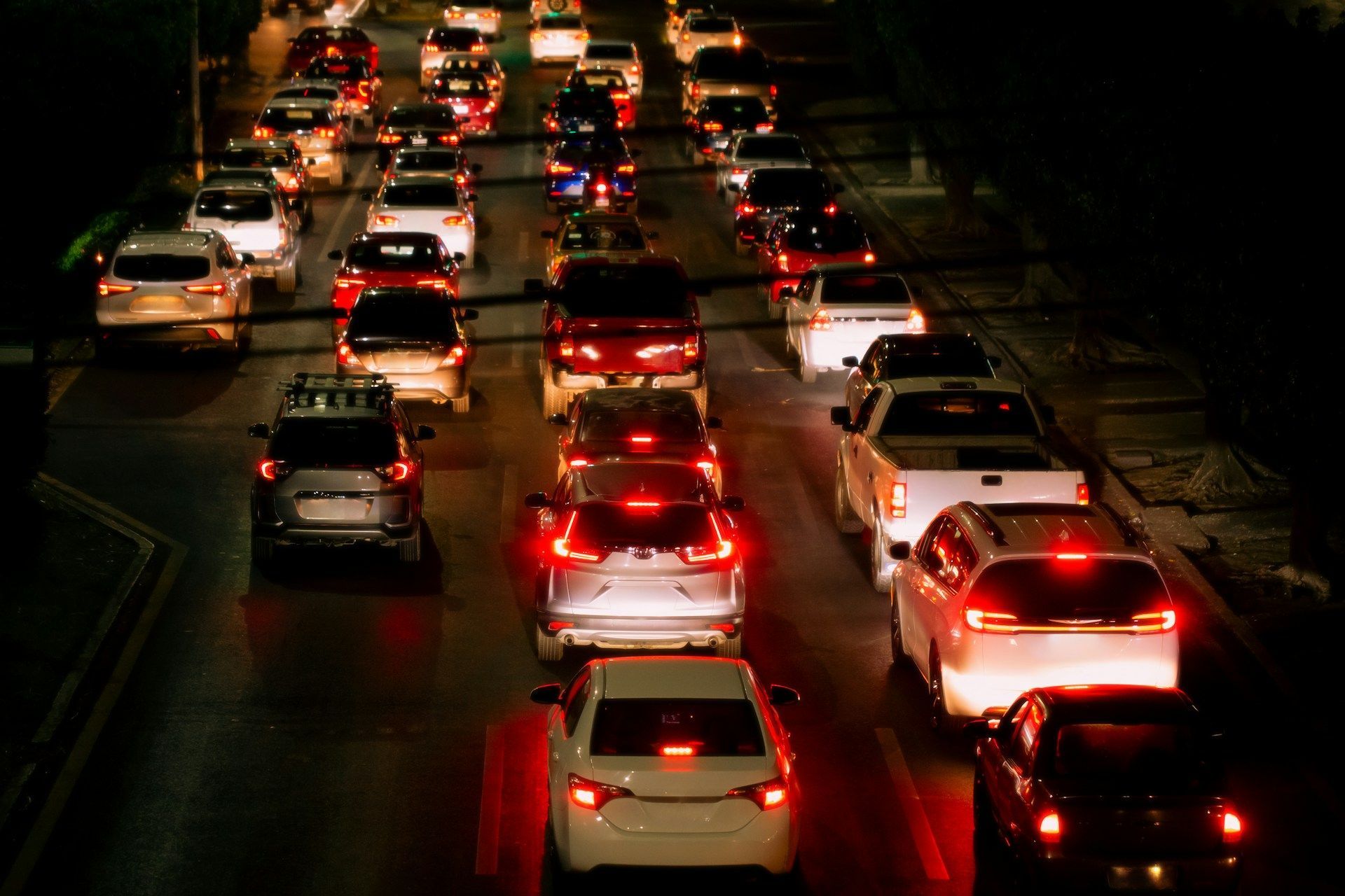 Traffic jam on a dark highway at night with red taillights and headlights visible.
