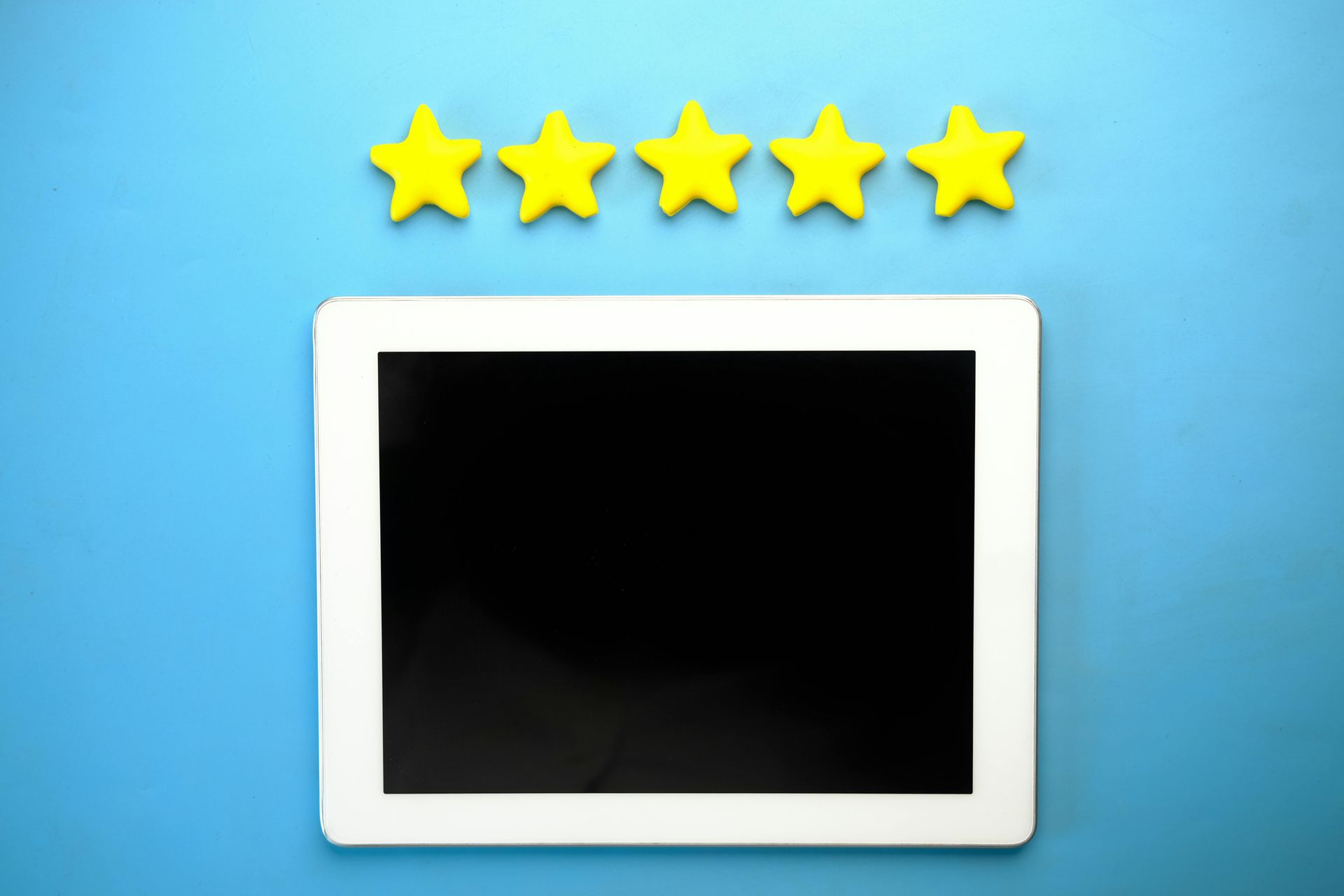 Tablet with black screen below five yellow stars on a blue background.