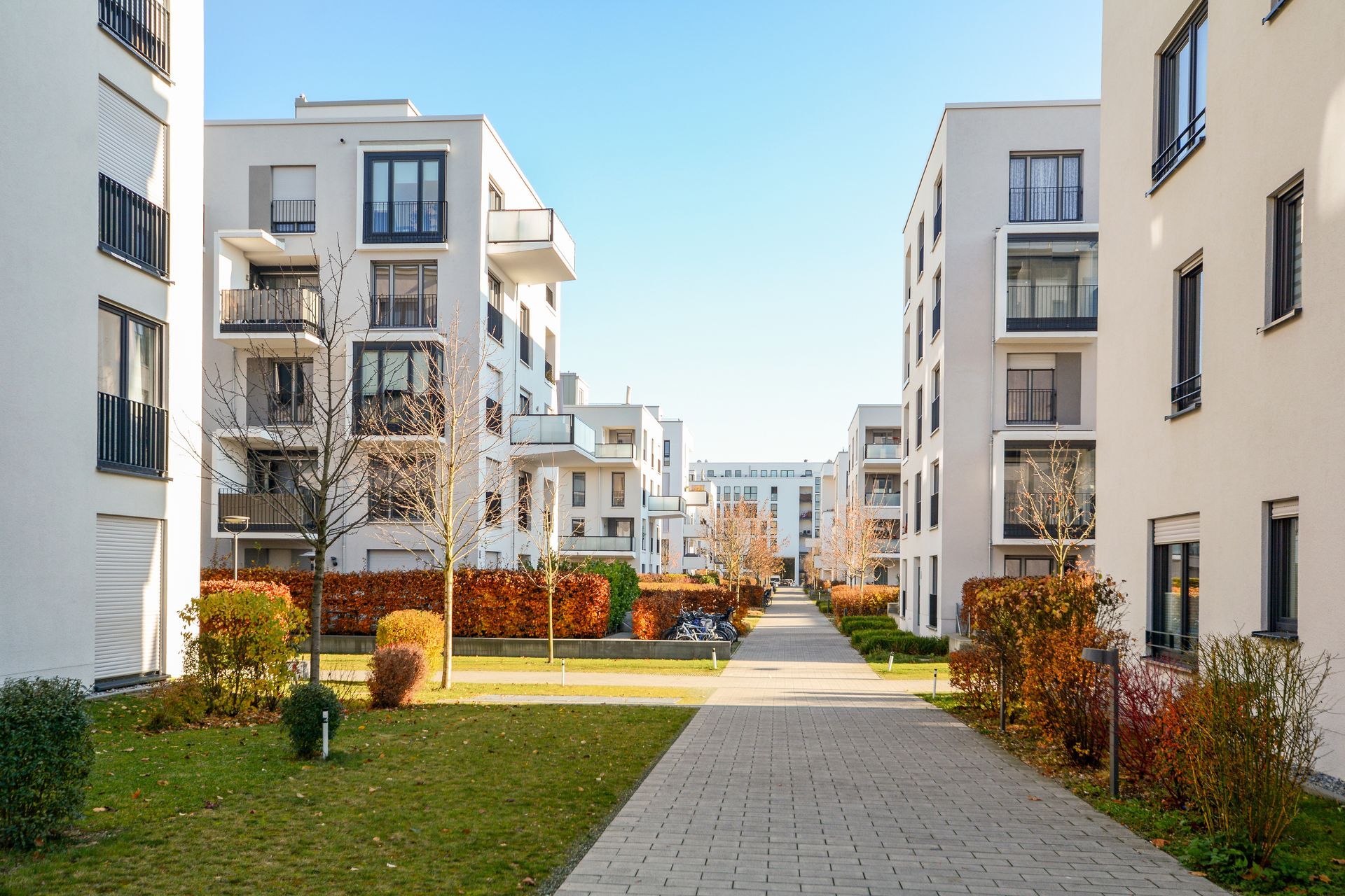 A row of apartment buildings in a residential area with a walkway between them.