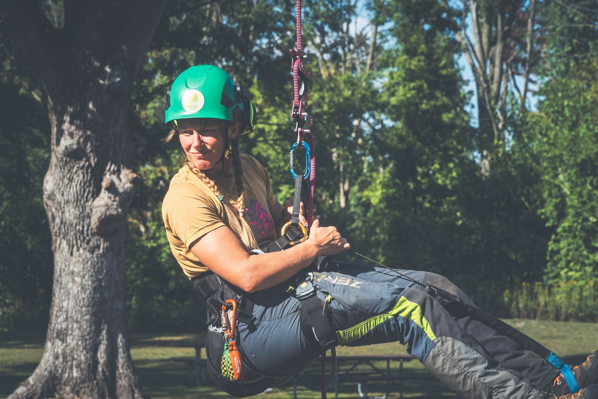 A man wearing a hard hat is sitting in a tree.
