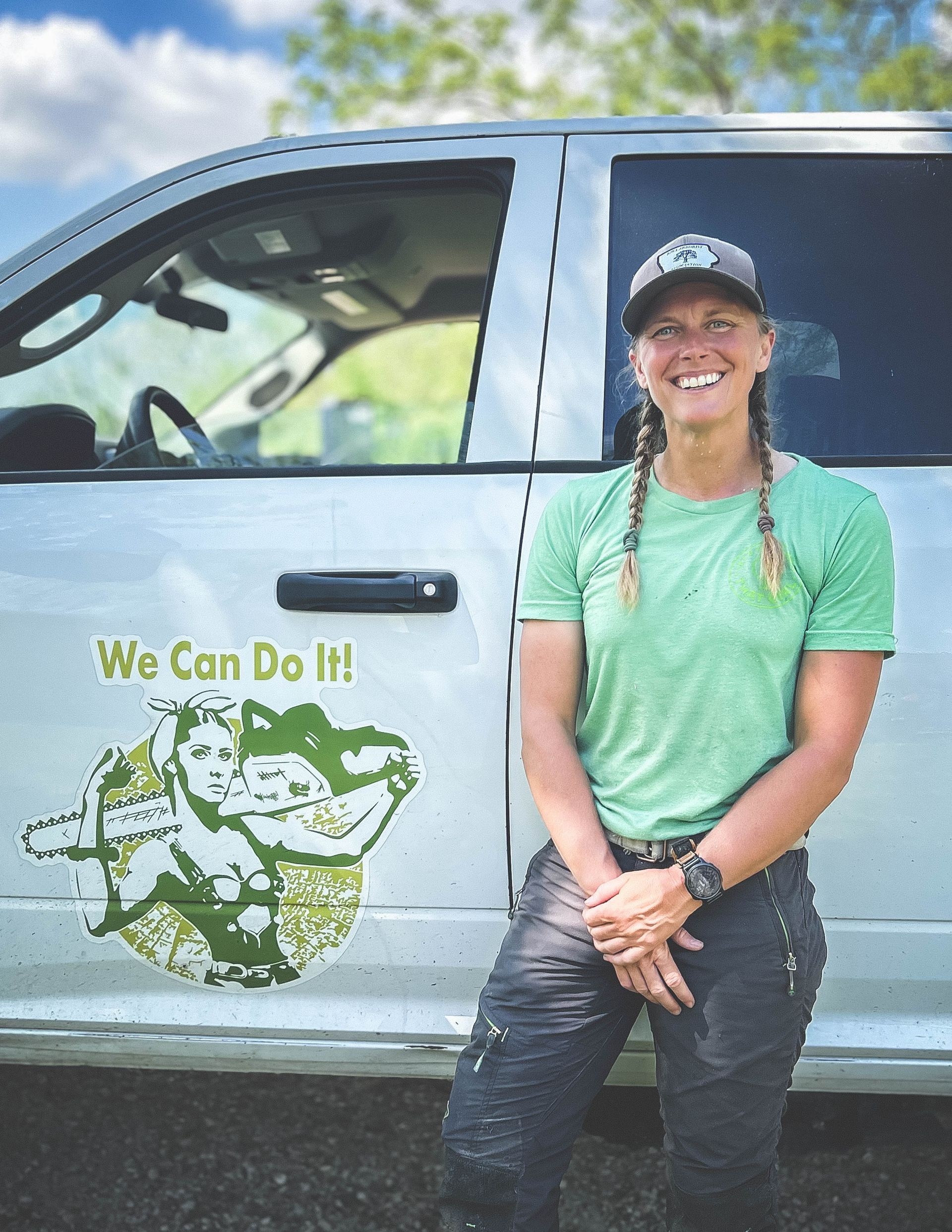 A woman in a green shirt is standing in front of a white truck.