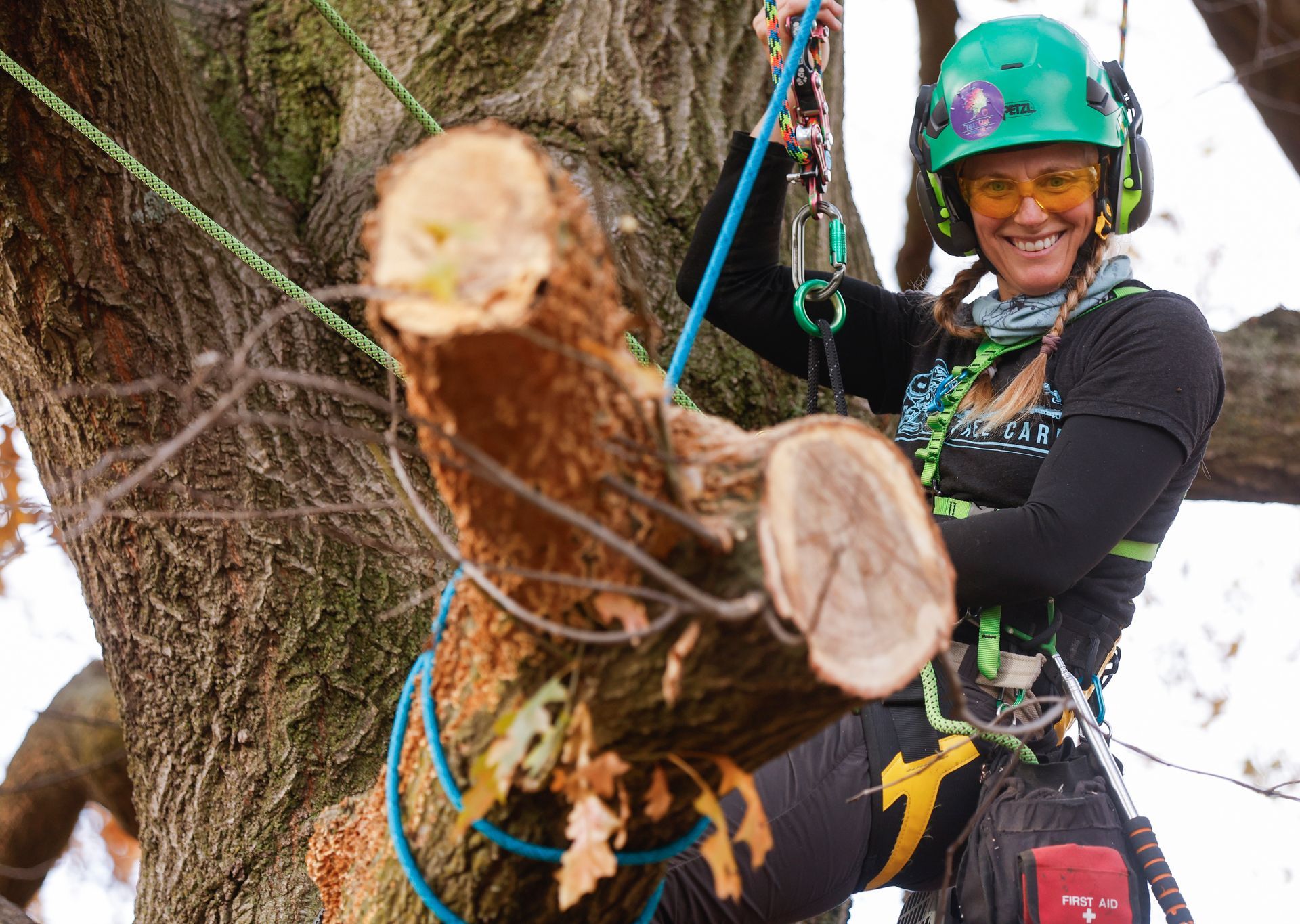 A woman in a green helmet is climbing a tree.