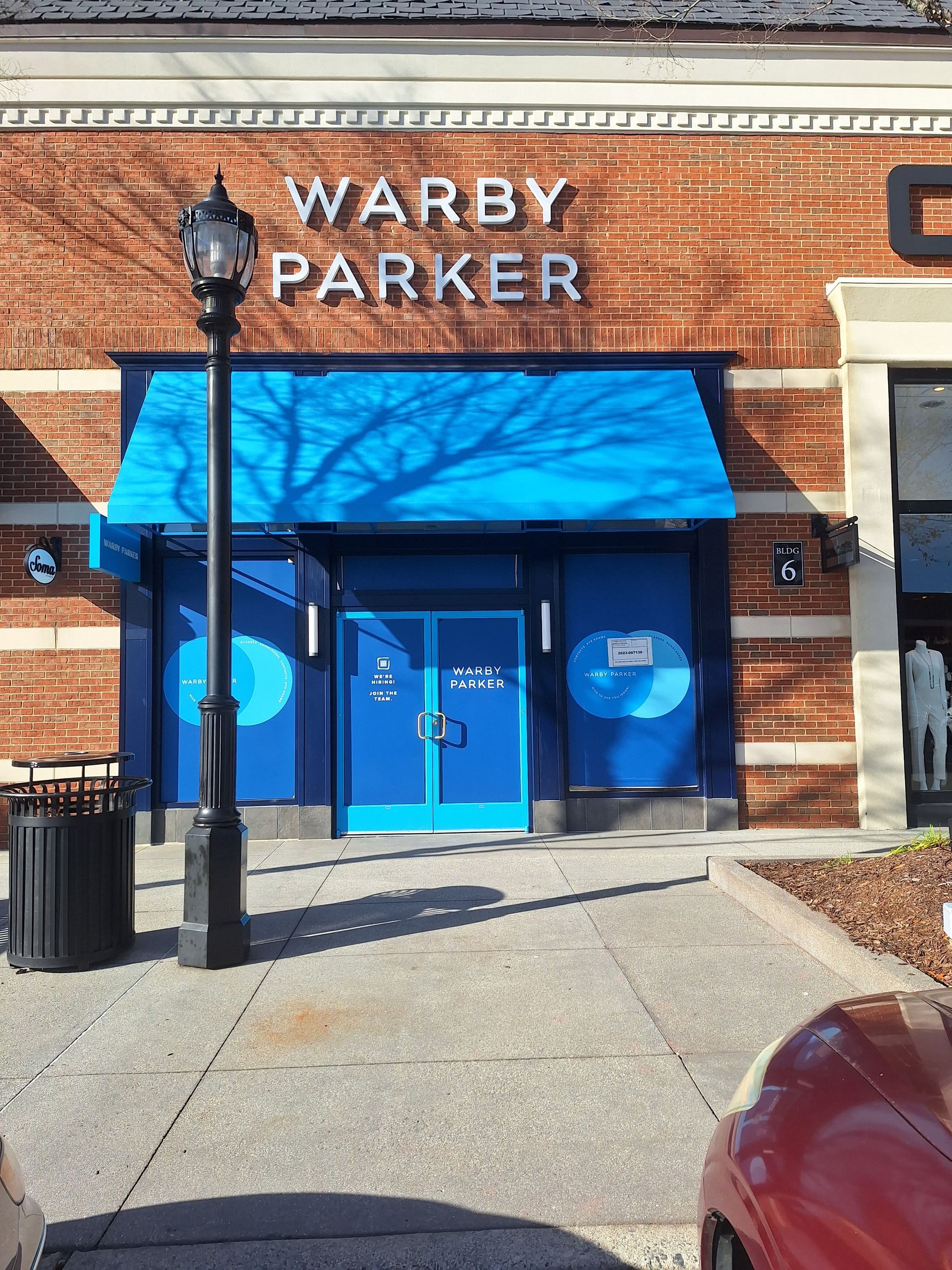 A warby parker store with a blue awning