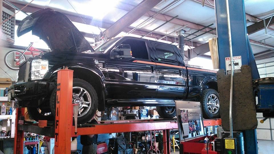 A black truck is sitting on a lift in a garage.