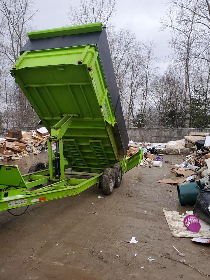 A green dumpster trailer is sitting in a pile of trash.