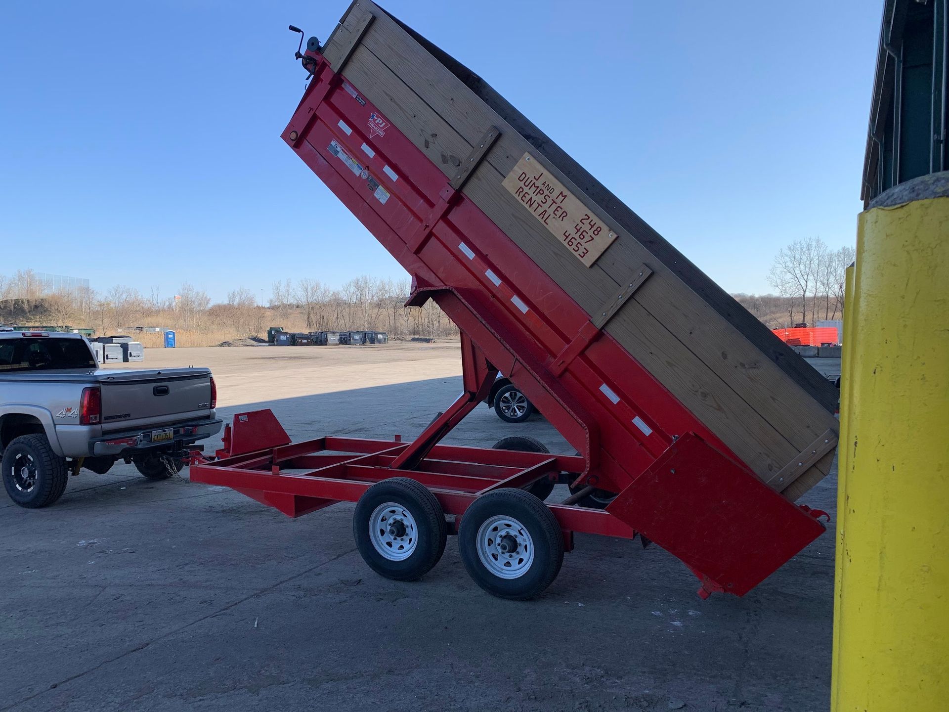 A dump trailer is being towed by a truck in a parking lot